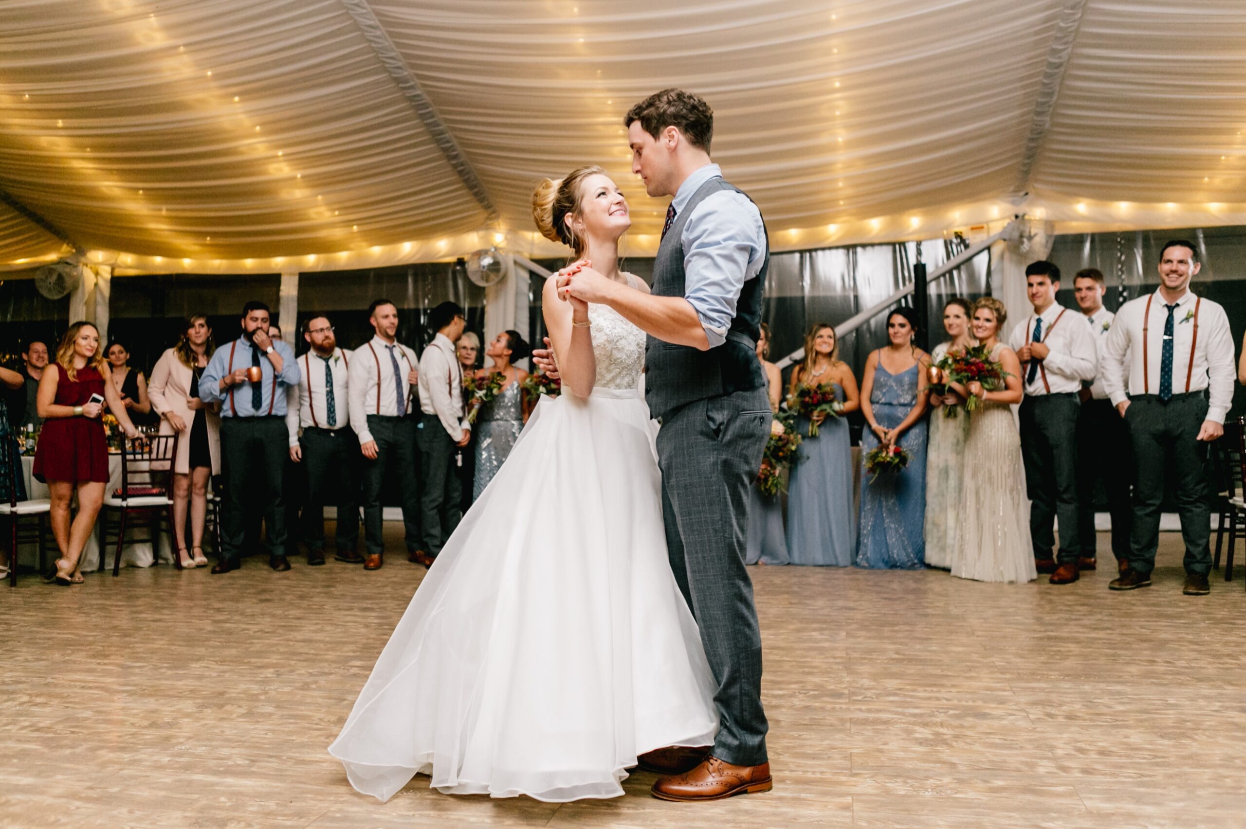 Bride and groom's first dance at a tented reception with twinkle lights