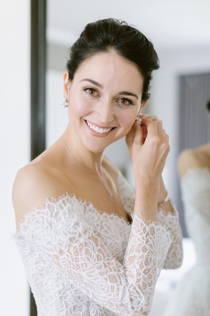 Bride putting on her pearl earrings while getting ready for a timeless wedding celebration