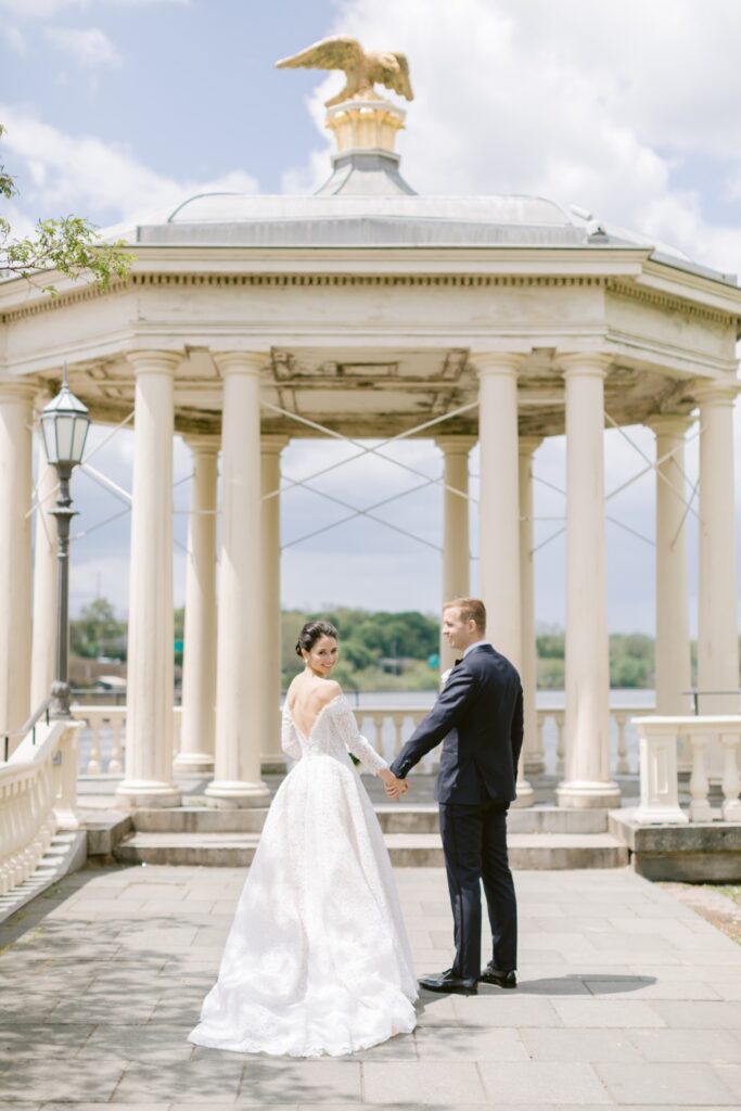 Bride and groom holding hands in front of the gazebo at Fairmount Water Works
