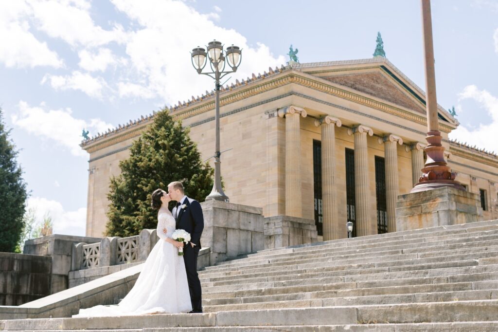 Bride and groom kissing in front of the Philadelphia Art Museum by Emily Wren Photography