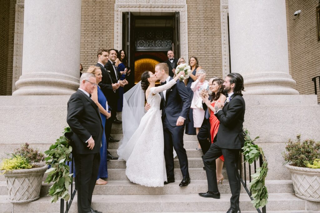 Bride and groom kissing on the church steps after a traditional spring church wedding ceremony