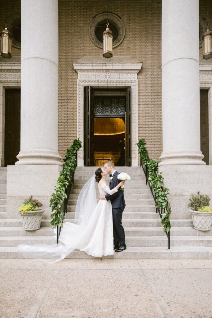 Bride and groom kissing on the steps of St. Patrick Church in Philadelphia