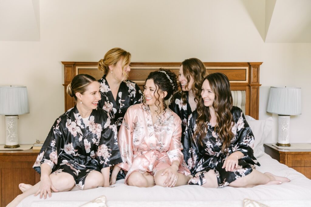 Bride and bridesmaids laughing while getting ready for a romantic spring wedding ceremony