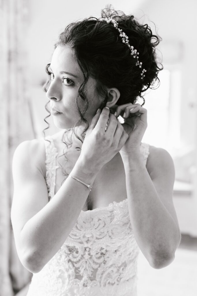 Bride putting on her jewelry while getting ready on the morning of her Main Line Pennsylvania wedding