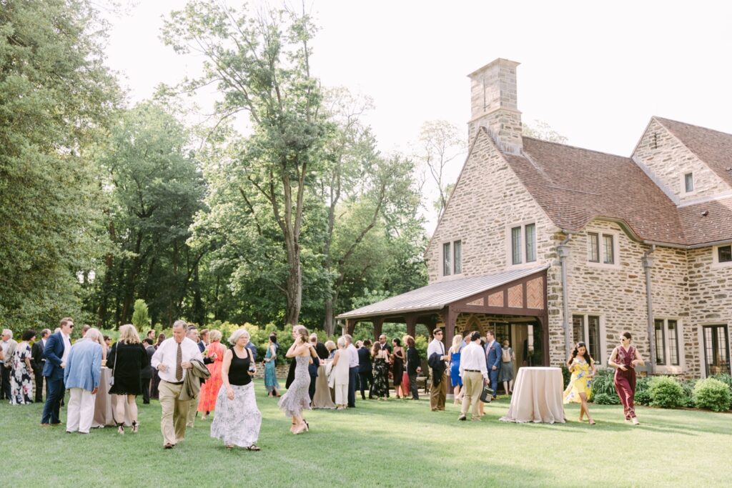 Guests at a backyard cocktail hour on a sunny spring wedding day on the Main Line in Pennsylvania