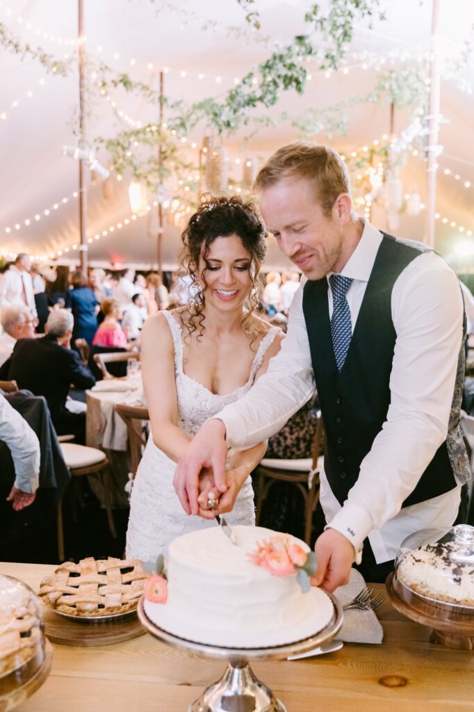 Newlyweds cutting the wedding cake during an intimate backyard wedding reception on a spring evening near Philadelphia