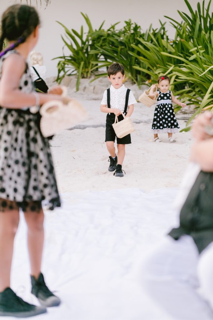 Flower girls walking down the aisle during a vibrant beach wedding in Tulum