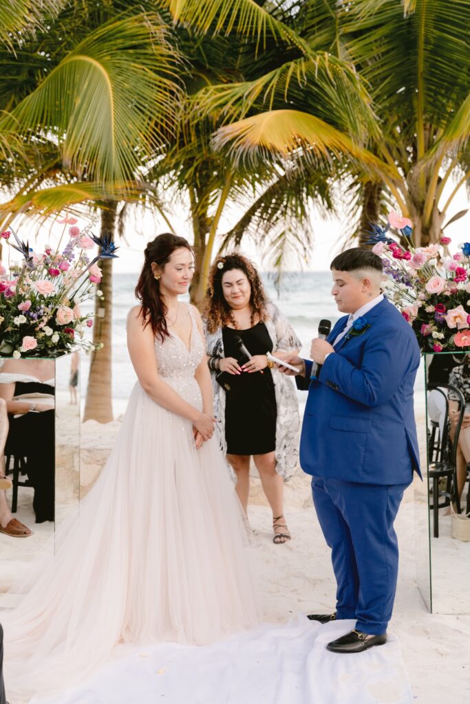 LGBTQ couple reads their vows during a modern oasis wedding ceremony on the beach in Mexico