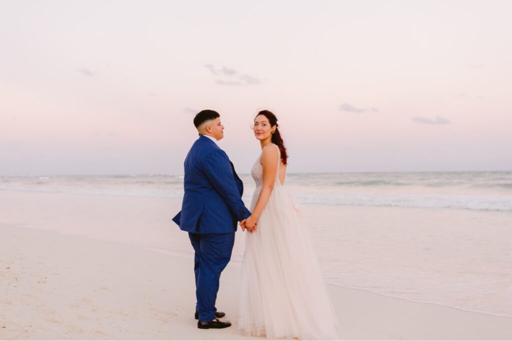 Brides holding hands on the beach at sunset at a modern destination wedding in Mexico