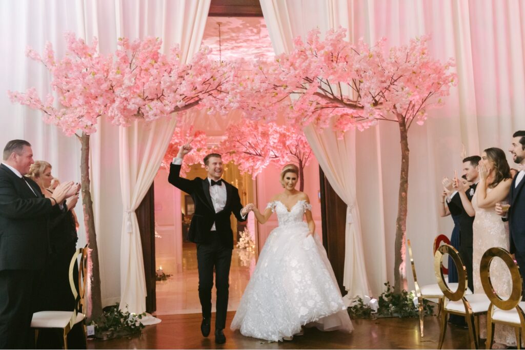 Bride and groom entering their opulent pink wedding reception