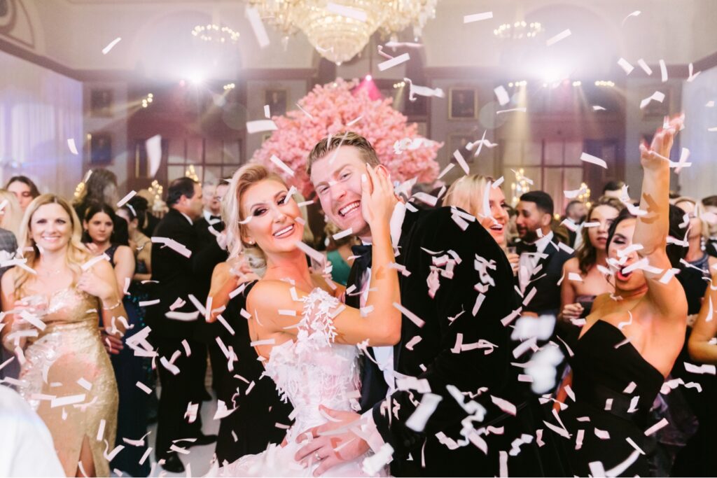 Bride and groom dancing as confetti rains down at their opulent wedding reception