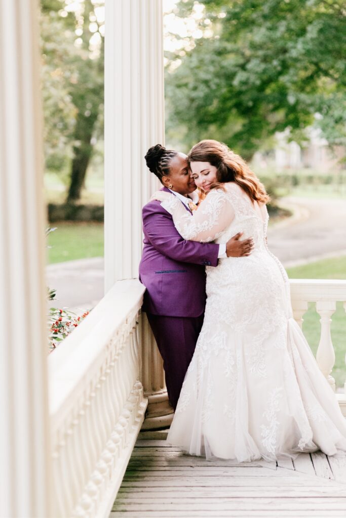 Brides kissing on the porch of Glen Foerd on their stunning fall wedding day