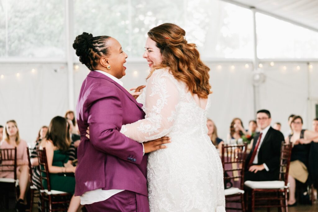 Interracial couple laughing during their first dance at a vibrant fall wedding reception