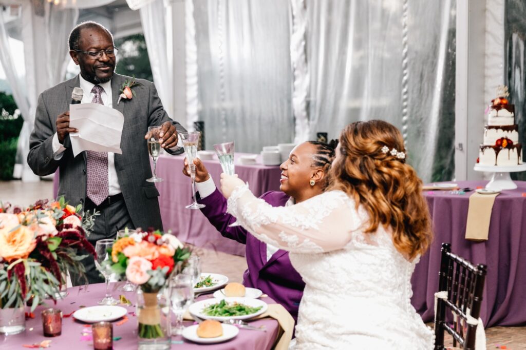 Interracial couple cheers after a wedding toast during their lively reception