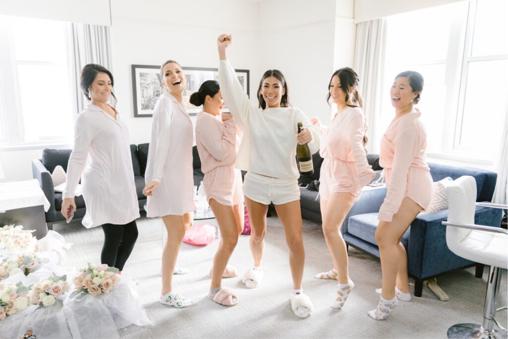 Bride and bridesmaids popping champagne before a luxury NYE wedding