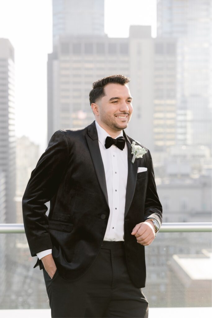 Groom smiling in front of the Philadelphia skyline on a winter wedding day