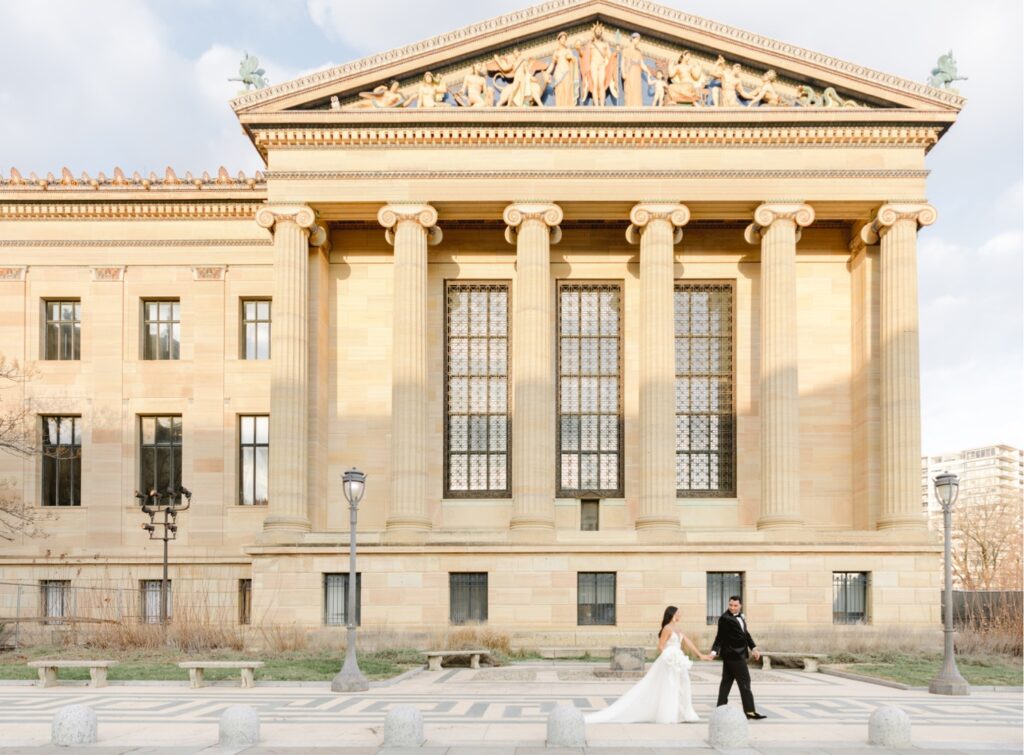 Bride and groom walking with the Philadelphia Art Museum behind them