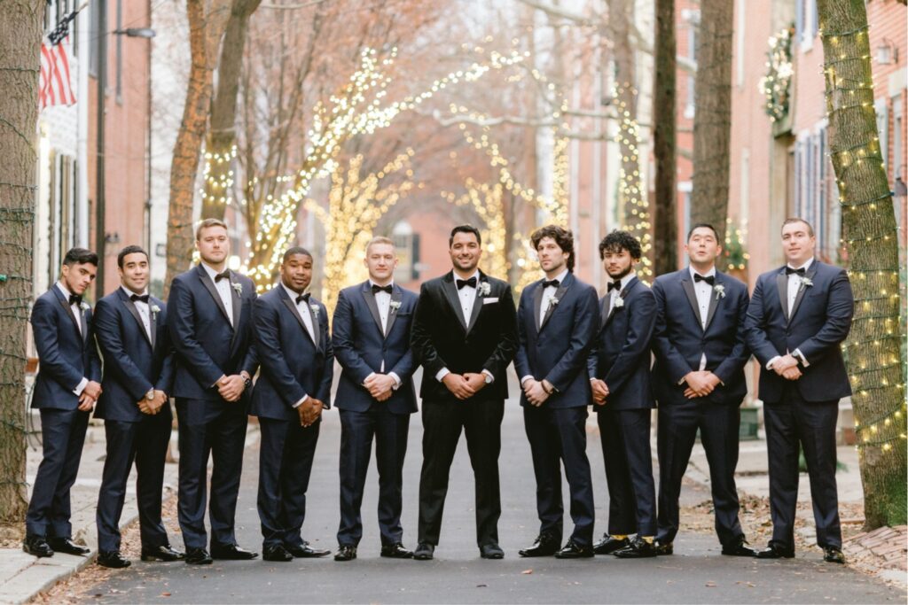 Groom and groomsmen on a city street with twinkle lights