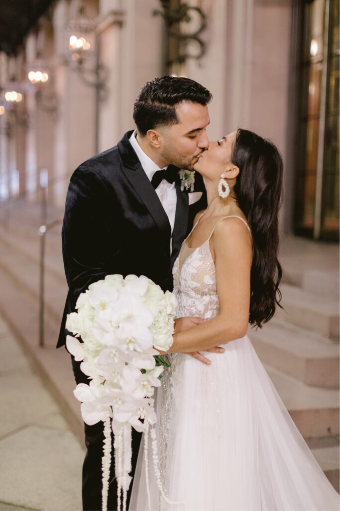 Newlyweds kissing outside of the Academy of Music in Philadelphia