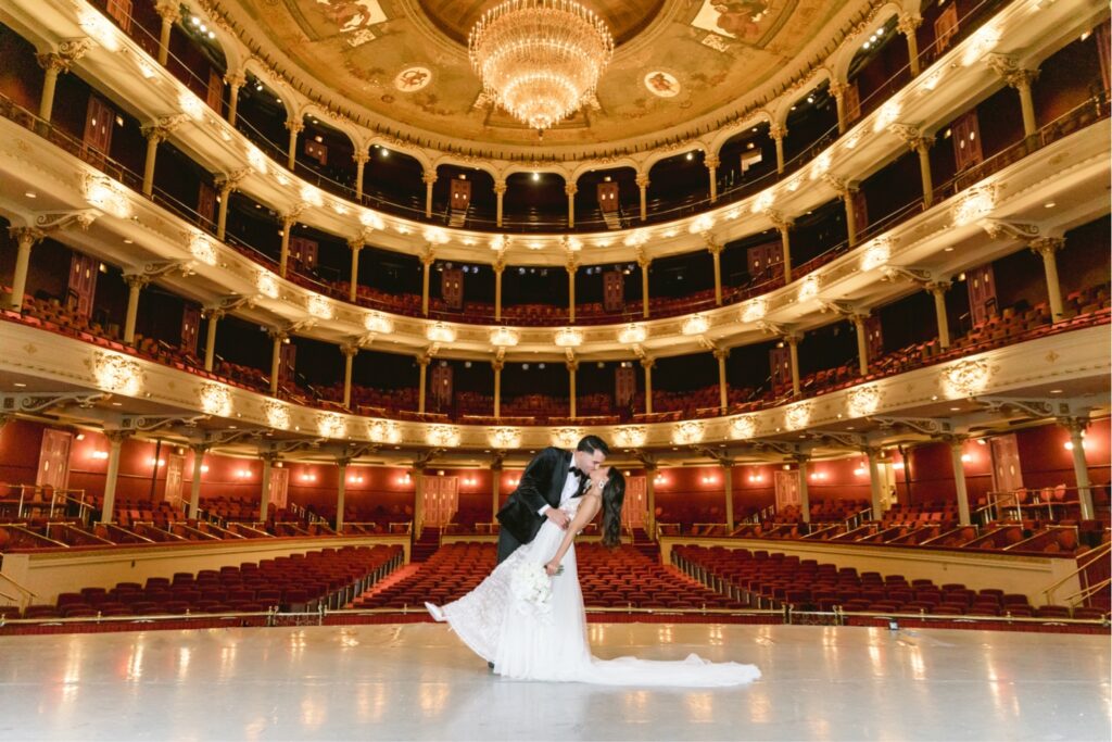 Bride and groom kissing on the stage of the Academy of Music