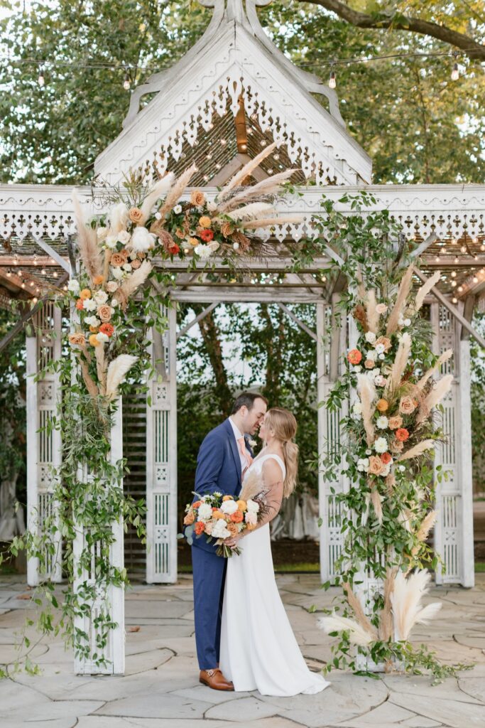 Bride and groom kissing in front of a luxury ceremony arch at Terrain