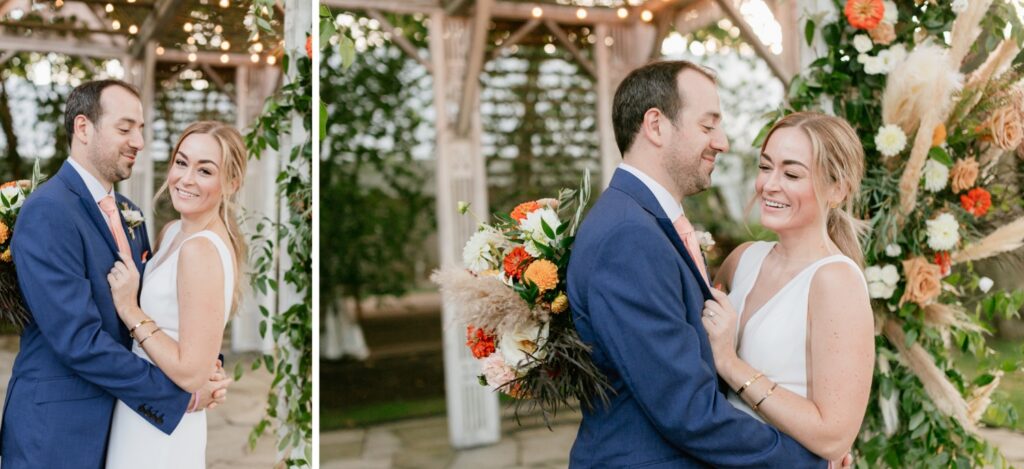 Newlyweds embrace under a vibrant floral arch during their covid micro wedding