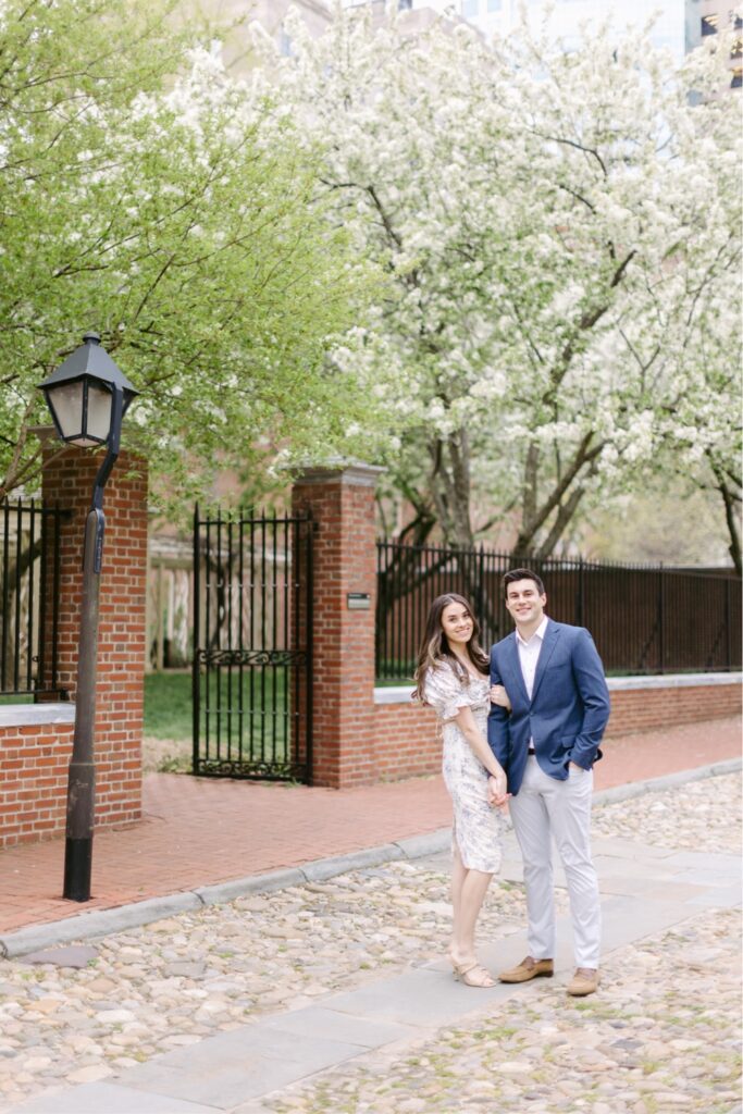 Couple smiling under budding spring trees during an Old City engagement session