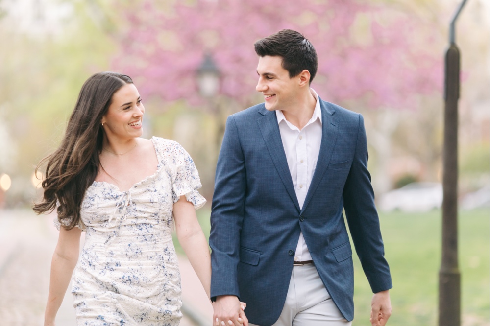 Couple walking with cherry blossoms in the background during a Philadelphia engagement session