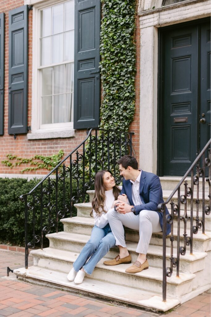 Engaged couple sitting on the steps of a historic Philadelphia row home