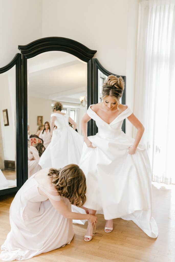 Bride getting help with her shoe while getting ready for a spring wedding