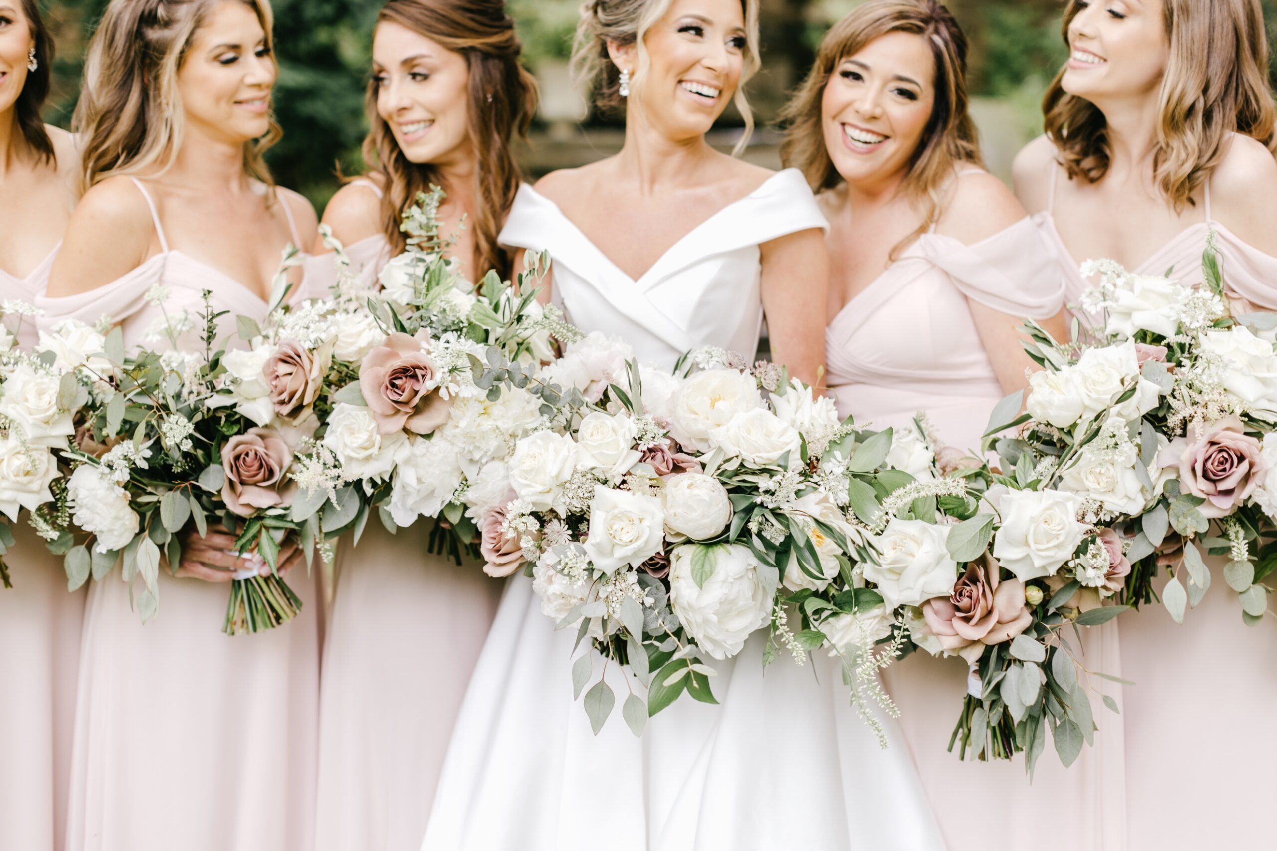 Bride and bridesmaids in blush dresses laughing together
