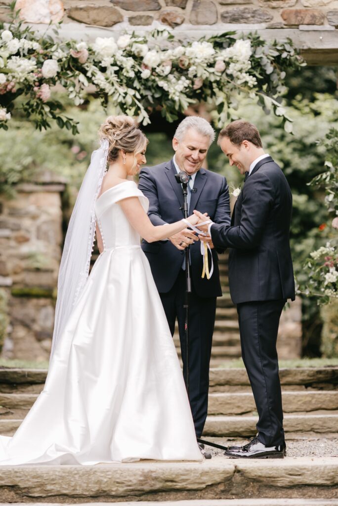 Bride and groom exchange rings at a garden wedding ceremony by Emily Wren Photography