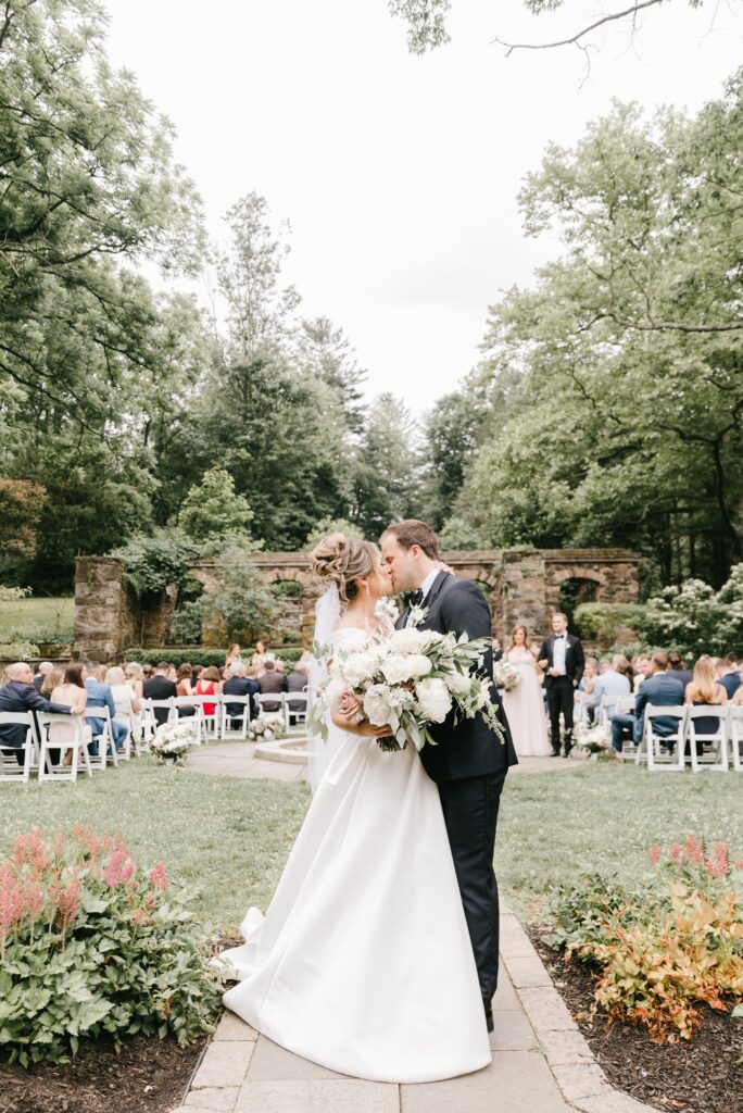 Bride and groom kissing during a spring garden wedding ceremony