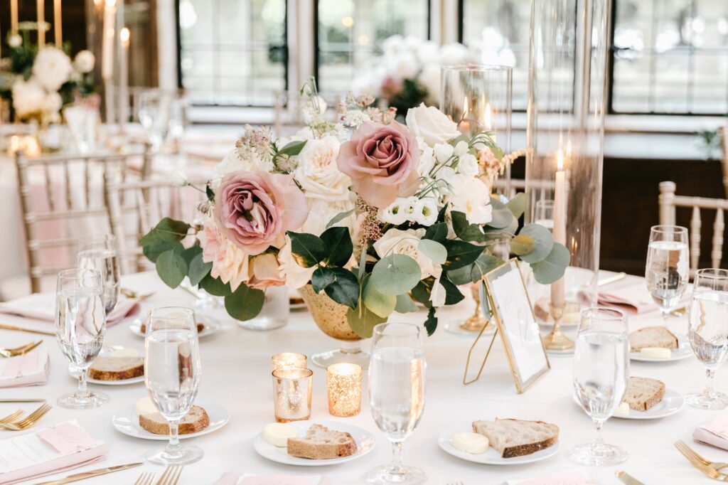 Spring floral arrangement with gold accents at an elegant wedding reception