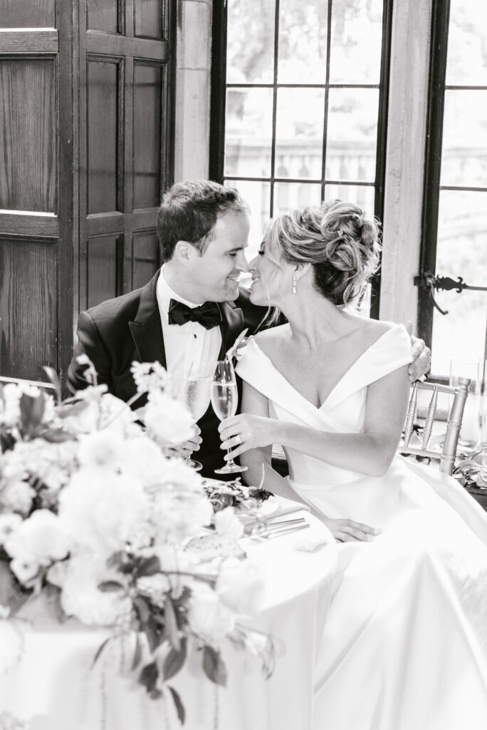 Bride and groom toasting champagne at their sweetheart table by Emily Wren Photography
