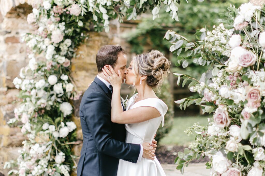Bride and groom kiss surrounded by spring flowers in Radnor