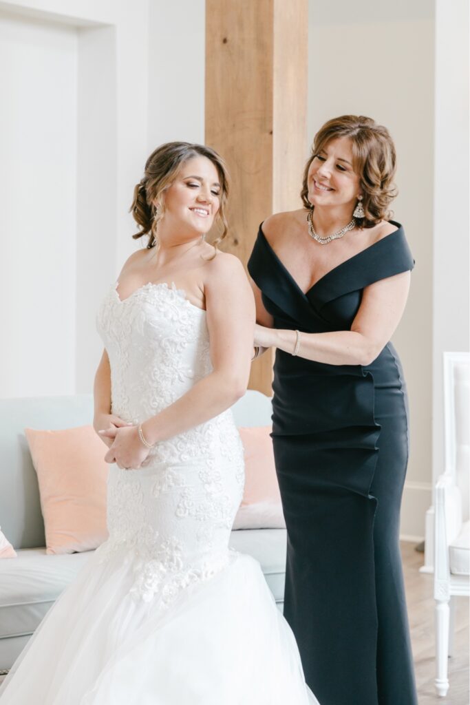 Mother of the bride helping the bride with her mermaid lace wedding gown