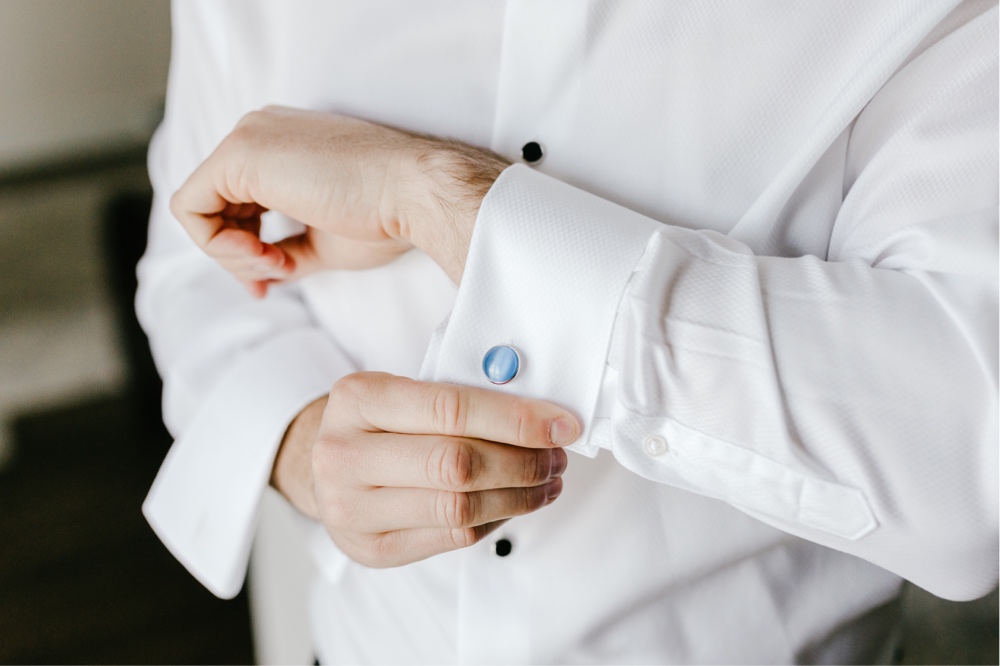 Groom putting on pearlescent blue cufflinks the morning of a winery wedding