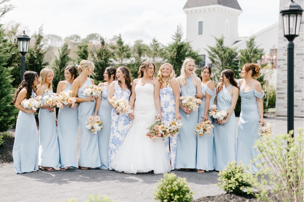 Bridesmaids in light blue dresses laughing on a spring wedding day at a winery near Cape May