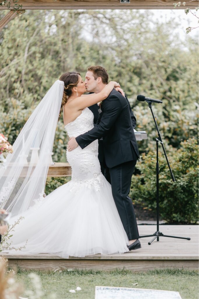 Bride and groom's first kiss at a spring outdoor wedding ceremony at a winery in New Jersey