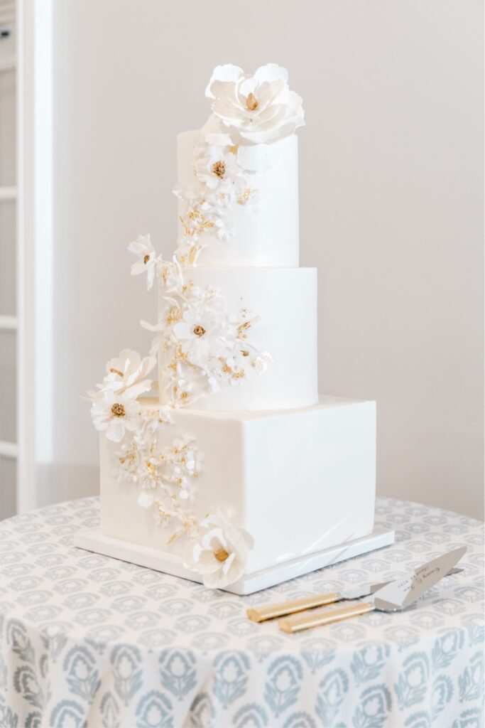 White wedding cake with gold accents and white flowers at a spring wedding in New Jersey