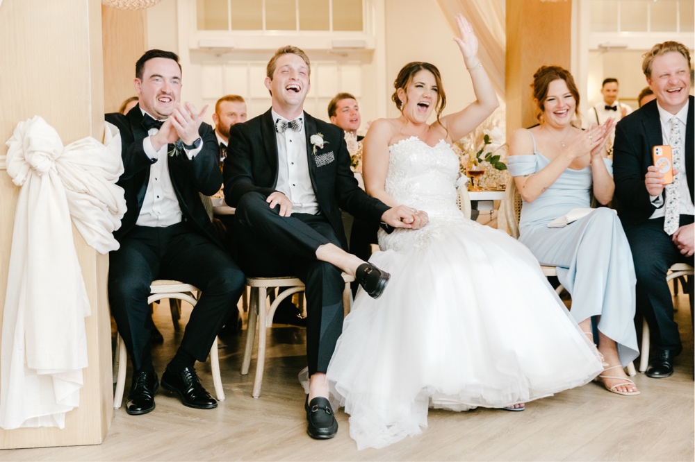 Bride and groom laughing during speeches at an indoor wedding reception