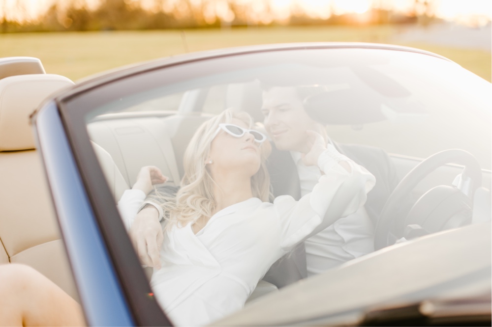Engaged couple embracing in a convertible car at sunset during a spring portrait session with Emily Wren Photography