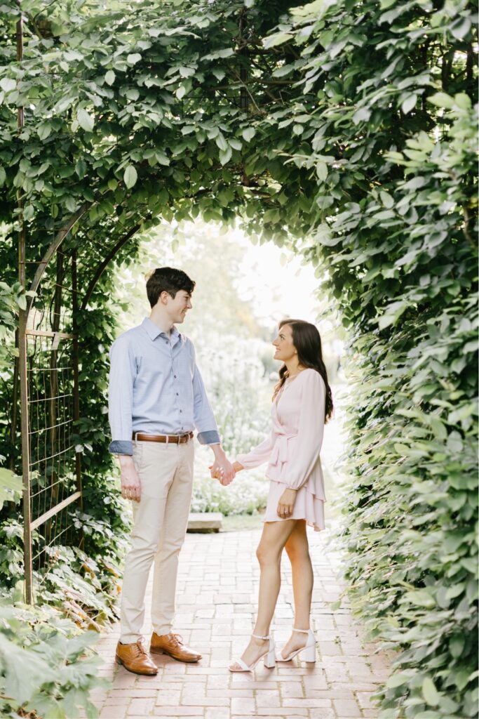 Couple underneath an arch filled with greenery at Longwood Gardens in Pennsylvania
