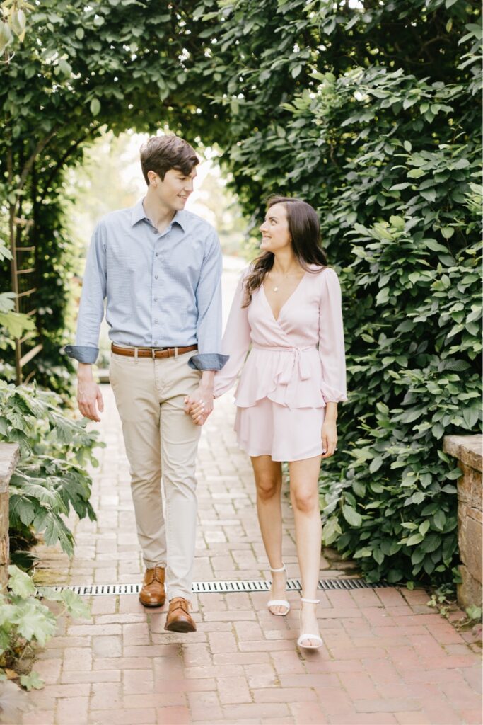 Couple walking on a path with greenery at a Longwood Gardens engagement session