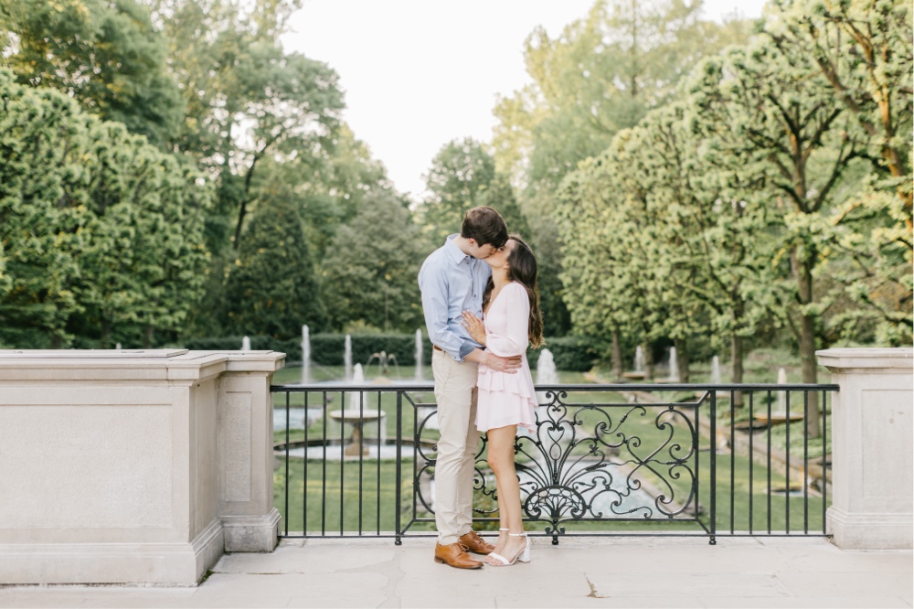 Couple kissing in front of garden fountains at an engagement shoot by Emily Wren Photography