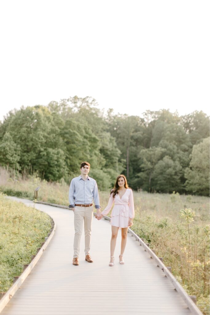 Couple holding hands at golden hour during a spring engagement shoot at Longwood Gardens