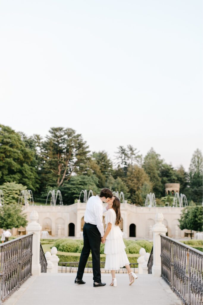 Couple kissing with garden fountains in the background at a Longwood Gardens engagement shoot