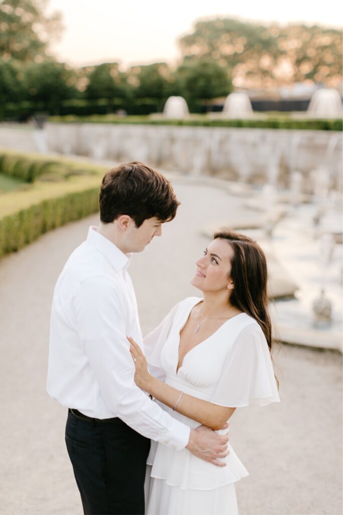 Couple smiling in a manicured garden during a sunset engagement session in Pennsylvania