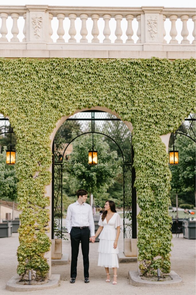 Couple holding hands under an arch filled with ivy at Longwood Gardens by Emily Wren Photography